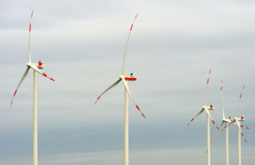 Das Foto zeigt fünf Windkraftanlagen mit rot-weißen Flügeln. Im Hintergrund ist der Himmel zu sehen.