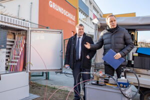 Das Foto zeigt Oberbürgermeister Dr. Sven Mißbach (l.) und den Vorstandsvorsitzenden der ENSO Energie Sachsen Ost AG, Dr. Frank Brinkmann (r.) vor der Grundschule Zabeltitz. Sie schauen in einen Verteilerkasten mit Glasfaserkabeln.