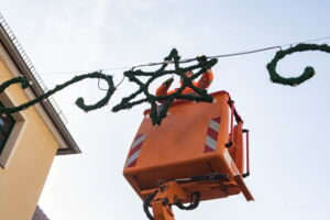 Das Foto zeigt einen Mitarbeiter des Bauhofes. Er steht in einem Hubsteiger. Von hier aus arbeitet er an einer Weihnachtsbeleuchtung in Sternenform.
