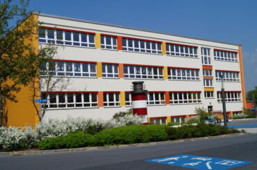 Auf dem Foto sieht man die Außenansicht der Grundschule "Am Schacht", davor die Einfahrt zum Kinderboulevard.